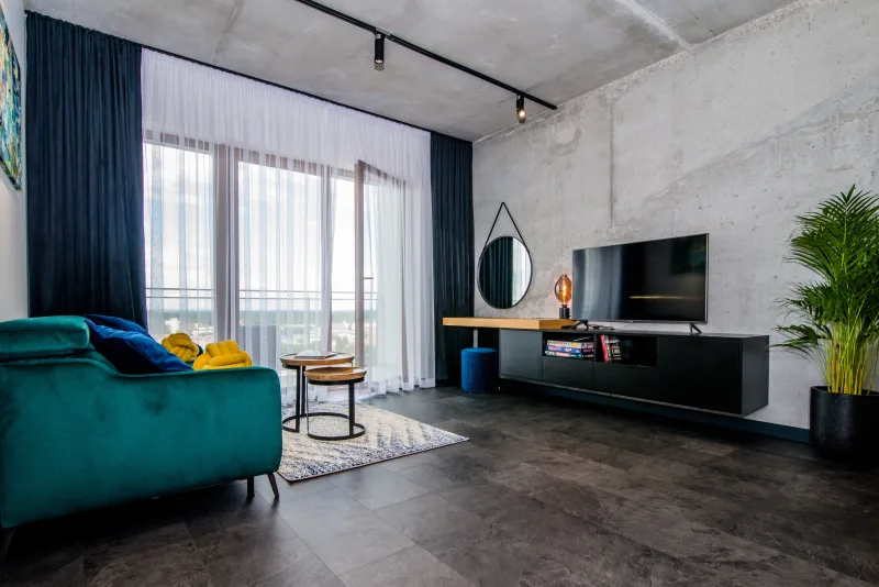 wnętrze apartamentu, widok salonu z sofą, tv, stolikiem kawowym i oknem balkonowym