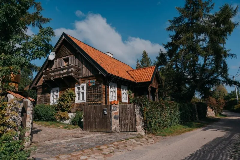 stary drewniany dom, otwarta brama wjazdowa, płot obrośnięty winobluszczem