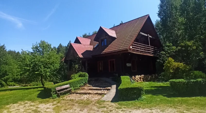 widok na ciemny drewniany dom, ławka i ścieżka z kamiennymi schody