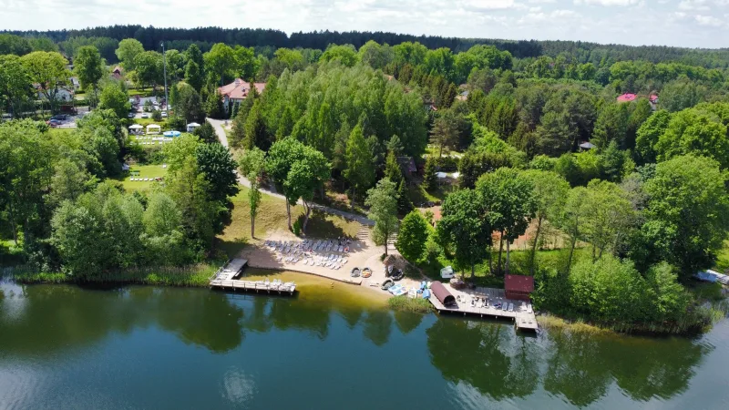 widok z lotu ptaka na plażę oraz teren z dużą ilością drzew i zieleni