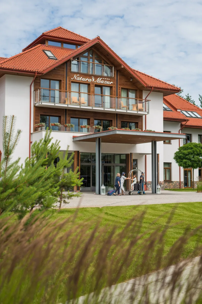 wejście główne do hotelu, na pierwszym planie trawy i drzewo