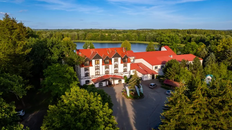 Budynek hotelowy na tle jeziora i lasów