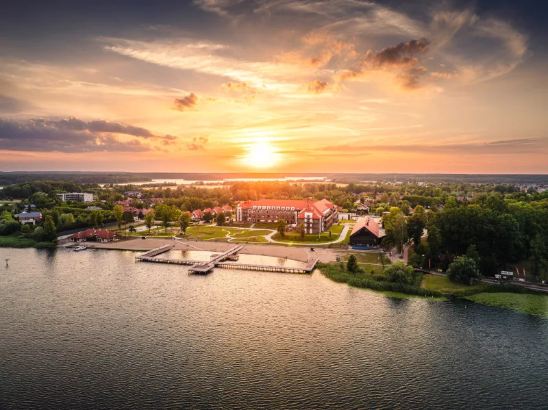 zdjęcie hotelu o zachodzie słońca, widoczne jezioro, plaża oraz molo