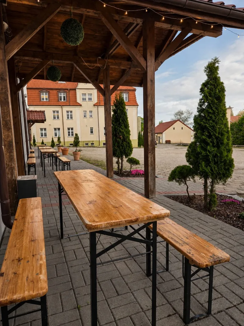 widok na budynek w oddali, na pierwszym planie ławki ii stoły