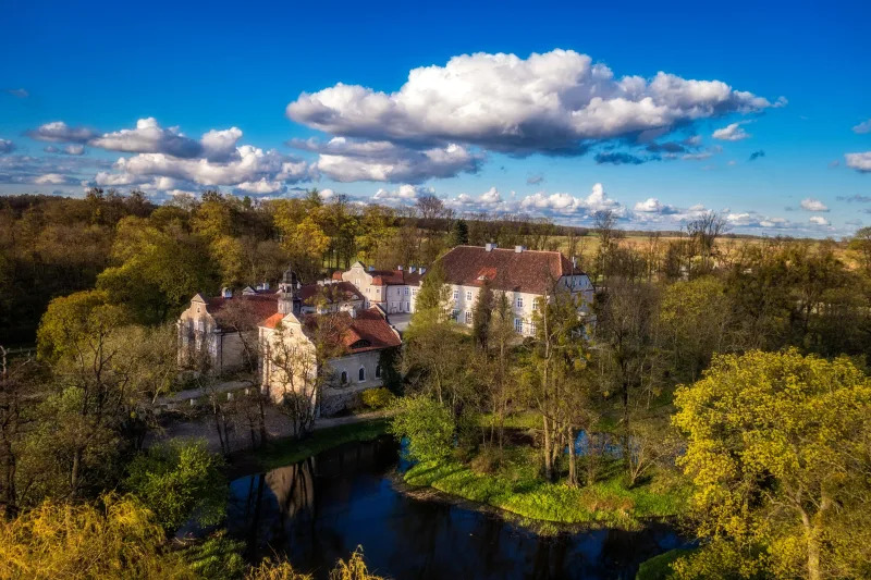 zdjęcie pensjonatu z lotu ptaka, zabytkowy budynek nad wodą wśród drzew