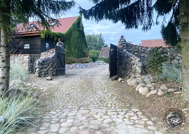 brama wjazdowa, w tle dom ze ścianą porośniętą winoroślą