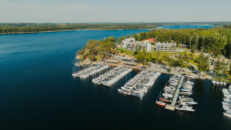 port jachtowy, budynki hotelowe, wokół jezioro i lasy